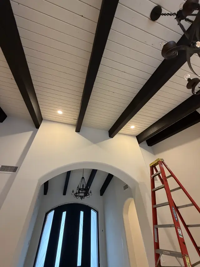 Beamed ceiling with recessed lighting above an arched doorway
